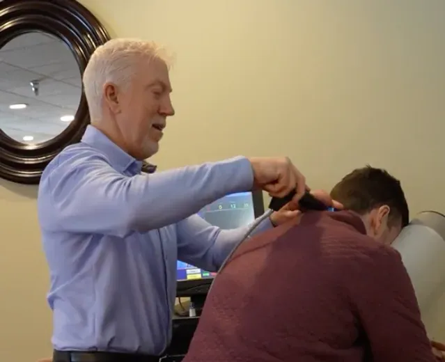 Dr. Mark Arsenault treating neck tension with SoftWave therapy