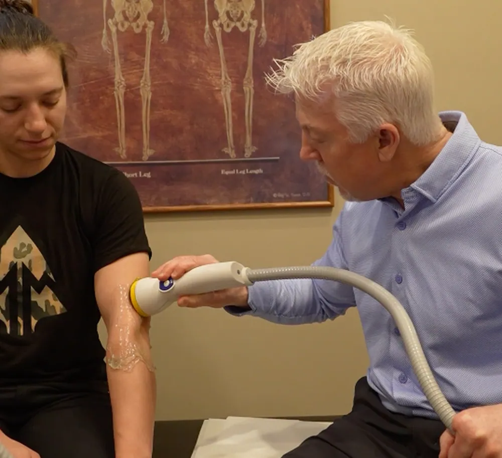 Dr. Mark Arsenault giving the woman a softwave therapy on the patient's arm