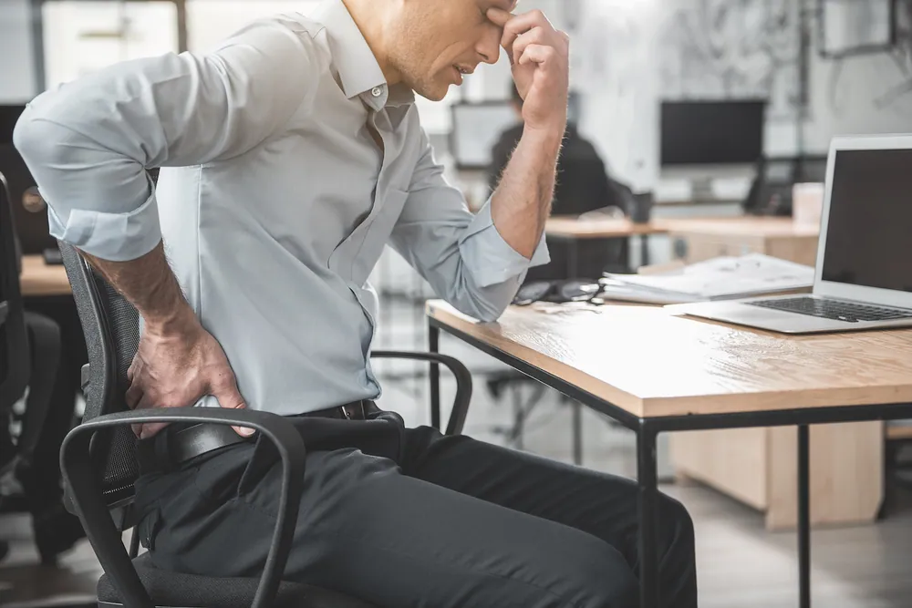 man suffering from lower back pain while doing his work