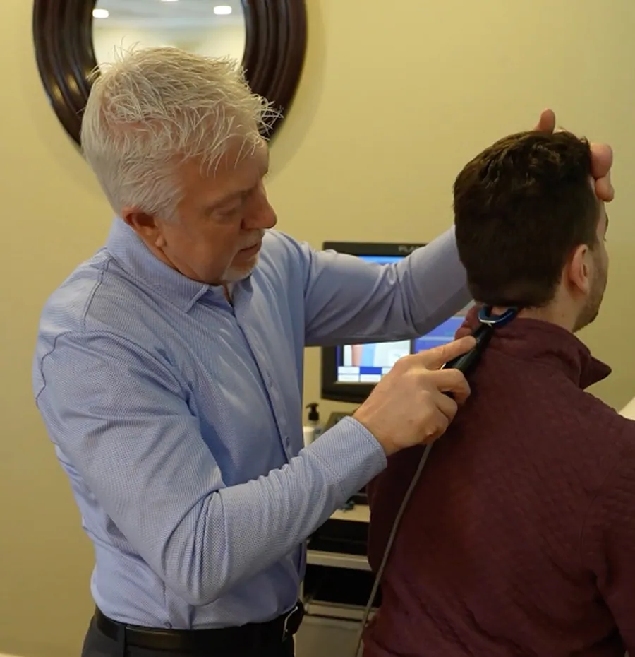 Dr. Mark Arsenault treating neck tension with SoftWave therapy